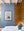 Framed picture of a bear on a blue wall next to a bed with wooden paneling.