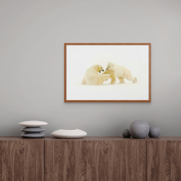 Framed artwork of two polar bears on a wall above a wooden cabinet with decorative items.