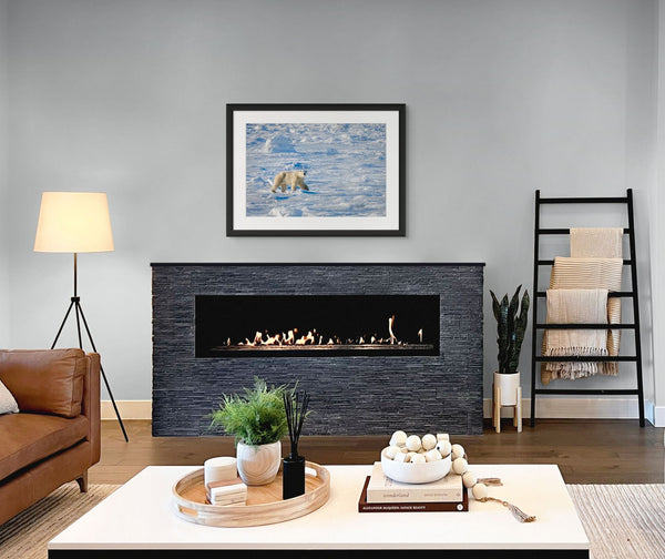 Modern living room with a fireplace, sofa, and decorative items. Photograph of polar bear displayed above fireplace.