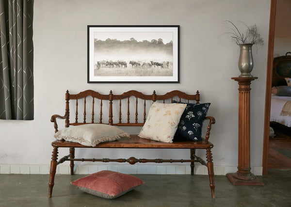 Wooden bench with cushions in a room with a framed picture on the wall.