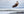 Bald eagle flying over a body of water with rocky shores.