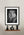 Framed black and white lion portrait on a wall above a wooden shelf with decorative vases.