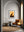 Framed artwork of a giraffe on a wall in a room with a brown leather chair and round table.